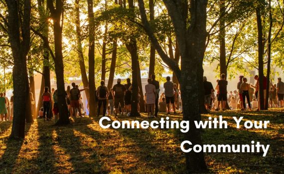 A large group of people gathered together in a sunlit forest during golden hour, with the text "Connecting with Your Community" overlaid in bold white lettering on the bottom right.