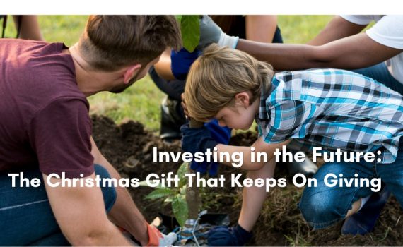 A young boy in a plaid shirt plants a small tree seedling with help from adults kneeling around him, with the heading Investing in the Future: The Christmas Gift That Keeps On Giving